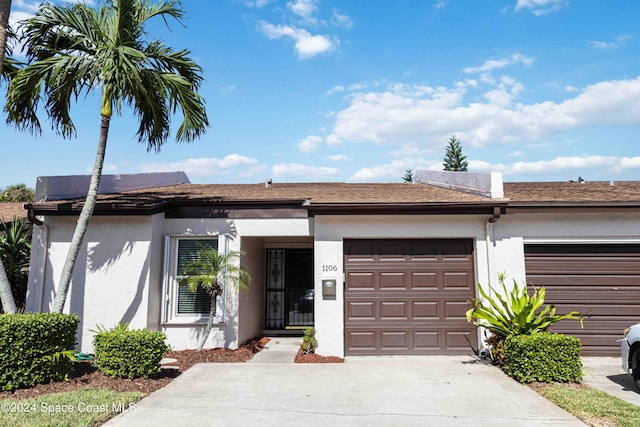 view of front of property with concrete driveway, an attached garage, and stucco siding