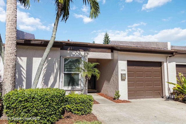 view of property featuring a garage, concrete driveway, and stucco siding