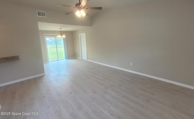 empty room with ceiling fan with notable chandelier, light wood finished floors, visible vents, and baseboards