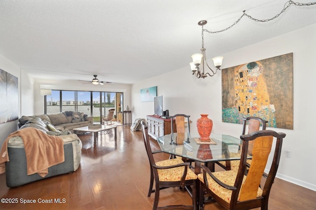 dining area with a textured ceiling, ceiling fan with notable chandelier, wood finished floors, and baseboards