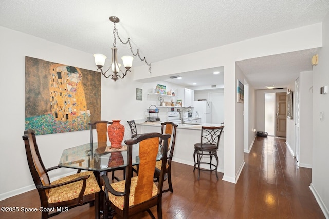 dining area with a notable chandelier, a textured ceiling, baseboards, and dark wood-style flooring