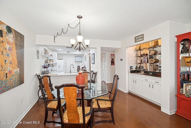 dining area featuring a notable chandelier, a textured ceiling, baseboards, and dark wood-style flooring