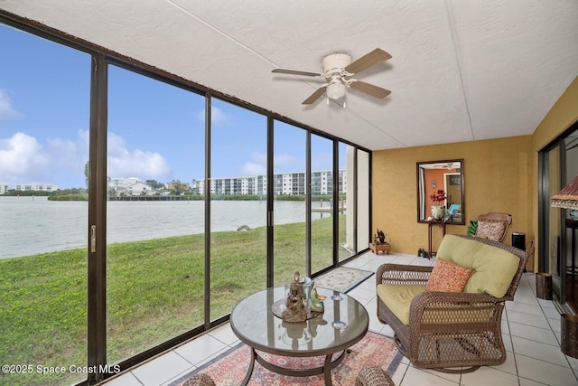 sunroom with ceiling fan and a water view