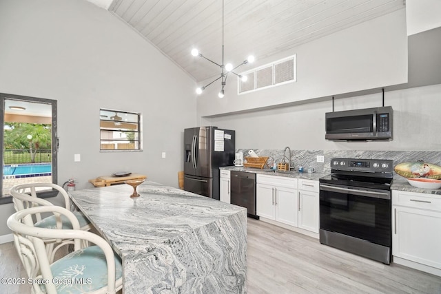 kitchen with appliances with stainless steel finishes, white cabinets, visible vents, and light stone countertops