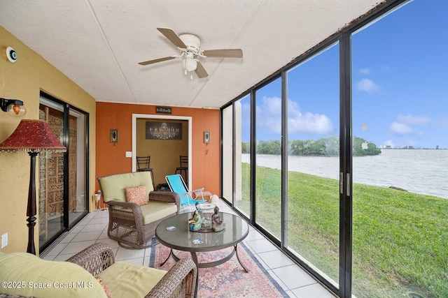 sunroom with ceiling fan and a water view