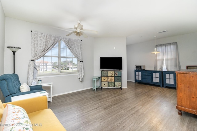 living area with ceiling fan, wood finished floors, visible vents, and baseboards