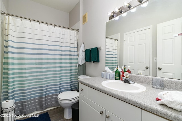 full bathroom with curtained shower, toilet, wood finished floors, vanity, and visible vents