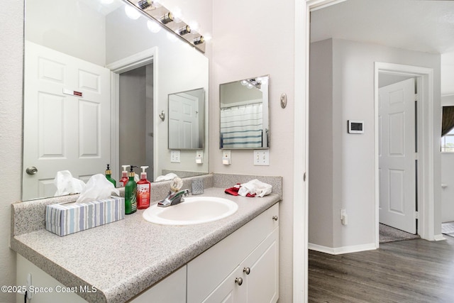 bathroom with wood finished floors, vanity, and baseboards