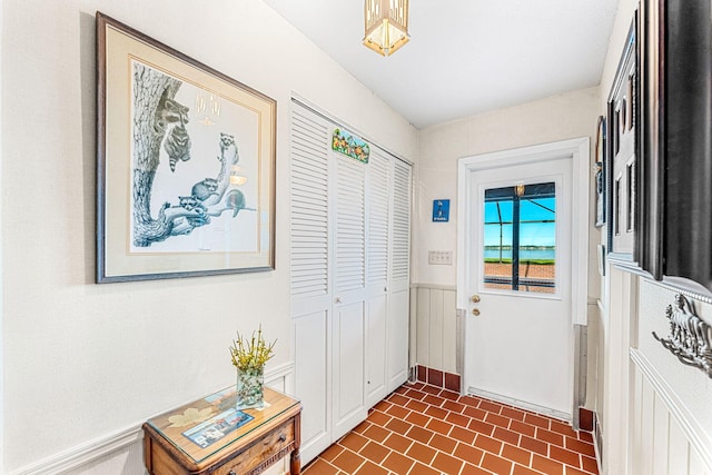 entryway featuring brick floor and wainscoting