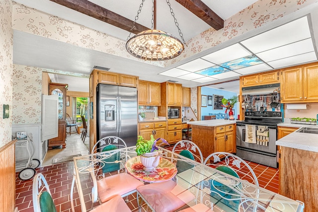 kitchen featuring wallpapered walls, wainscoting, a center island, stainless steel appliances, and light countertops