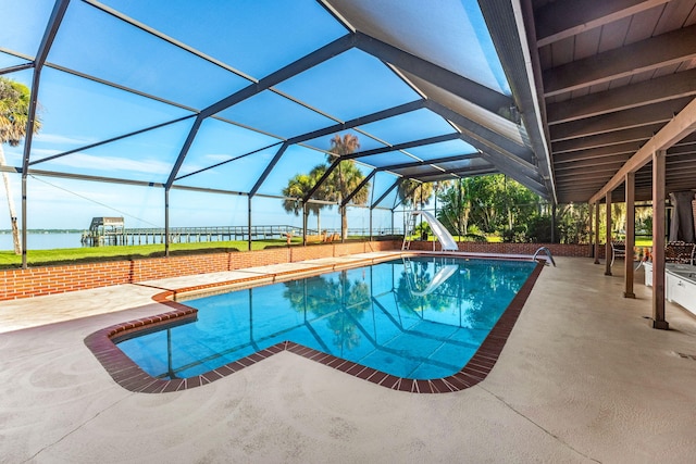 pool featuring a patio area, glass enclosure, a water slide, and a water view