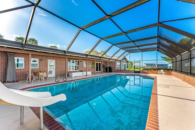 outdoor pool featuring glass enclosure, a water slide, and a patio