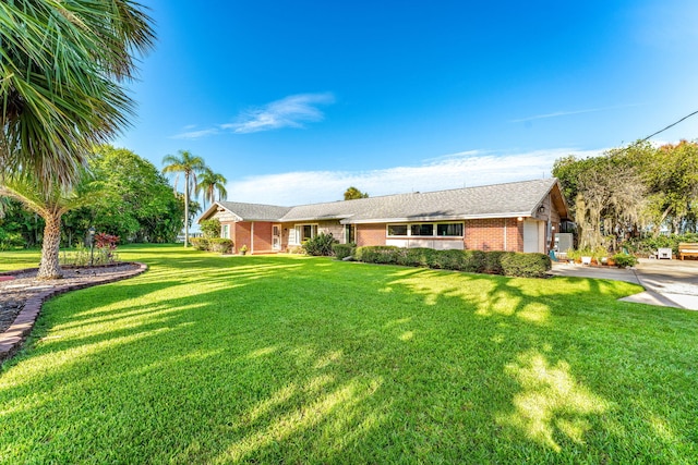 single story home with a garage, a front yard, and brick siding