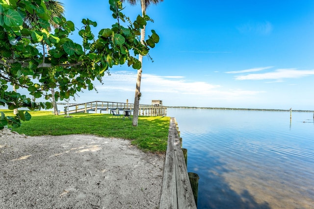 dock area with a lawn and a water view