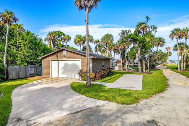 view of home's exterior featuring fence, a detached garage, an outdoor structure, and a lawn