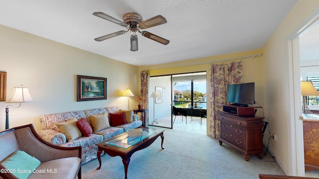 living room with a ceiling fan, carpet, and a textured ceiling