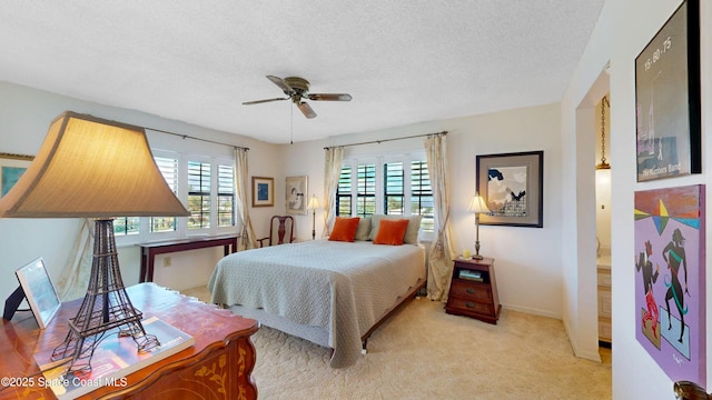 bedroom with multiple windows, a ceiling fan, a textured ceiling, and light colored carpet