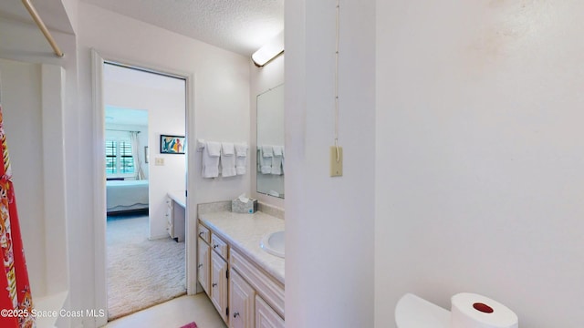 ensuite bathroom featuring connected bathroom, toilet, a shower with curtain, a textured ceiling, and vanity