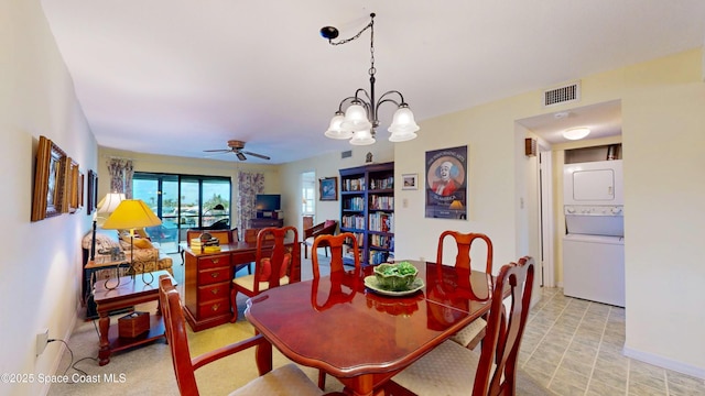 dining area featuring stacked washer and dryer, visible vents, and ceiling fan with notable chandelier