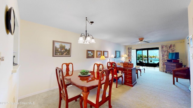 dining room featuring light carpet, baseboards, and ceiling fan with notable chandelier