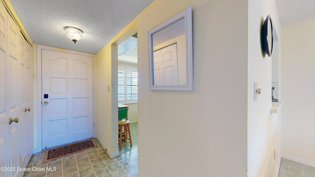 foyer featuring a textured ceiling and baseboards