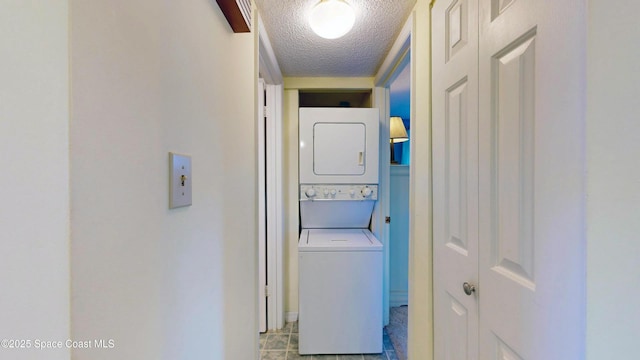 washroom featuring stacked washer and clothes dryer, a textured ceiling, and laundry area