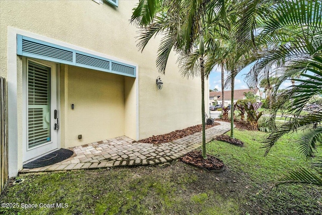 doorway to property with a lawn and stucco siding