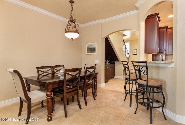 dining area with light tile patterned floors, baseboards, arched walkways, and ornamental molding