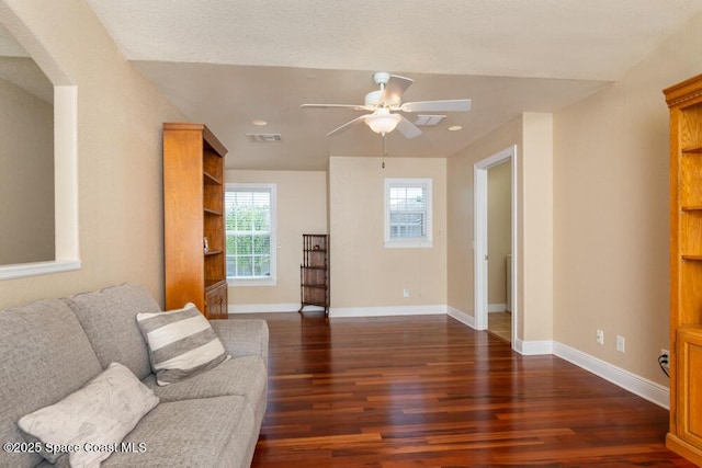 living room with baseboards, visible vents, arched walkways, a ceiling fan, and dark wood-style floors