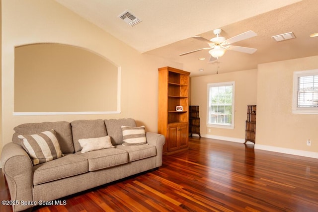 living area with dark wood finished floors, visible vents, and baseboards