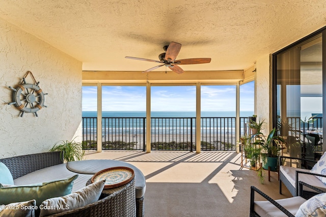 sunroom / solarium with carpet flooring, a textured wall, a water view, and a wealth of natural light