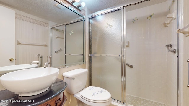 full bath with a textured ceiling, a stall shower, vanity, and toilet