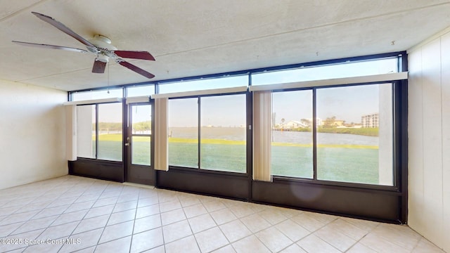 unfurnished sunroom featuring a water view, a wealth of natural light, and a ceiling fan