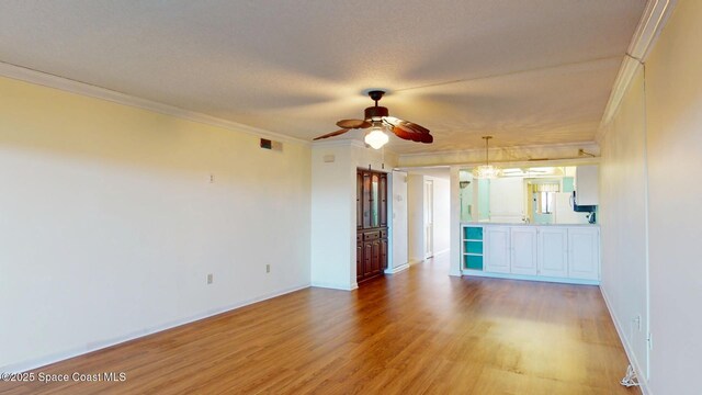 spare room with light wood-style flooring, visible vents, baseboards, a ceiling fan, and ornamental molding