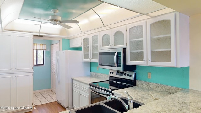 kitchen featuring glass insert cabinets, white cabinetry, stainless steel appliances, and a sink