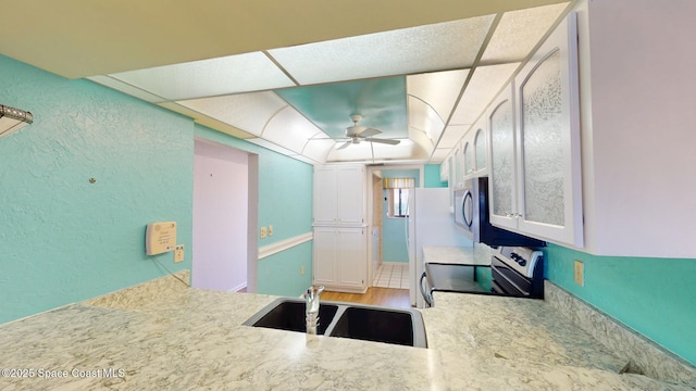 kitchen with ceiling fan, wood finished floors, a sink, light countertops, and appliances with stainless steel finishes