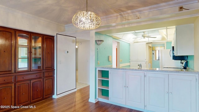 bathroom featuring ornamental molding, a sink, wood finished floors, baseboards, and ceiling fan with notable chandelier