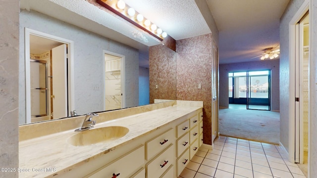 full bathroom with a ceiling fan, a textured ceiling, vanity, baseboards, and tile patterned floors