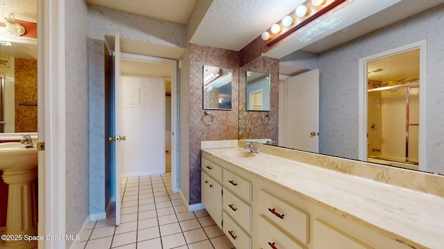 full bathroom featuring tile patterned flooring, a textured ceiling, a sink, and a shower with shower door