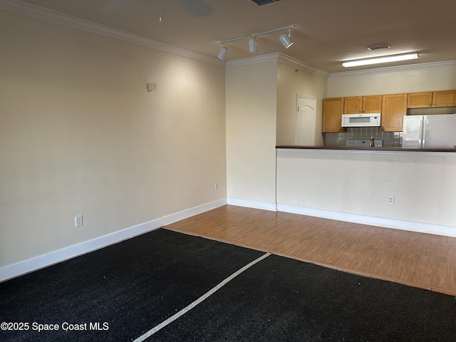 spare room with ornamental molding, ceiling fan, baseboards, and wood finished floors