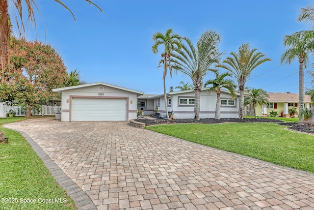 ranch-style house with stucco siding, decorative driveway, fence, a front yard, and a garage