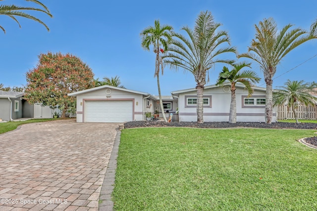 view of front of house with fence, stucco siding, a front lawn, a garage, and decorative driveway