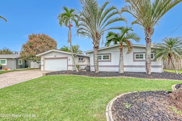 view of front of house featuring fence, an attached garage, stucco siding, a front lawn, and decorative driveway