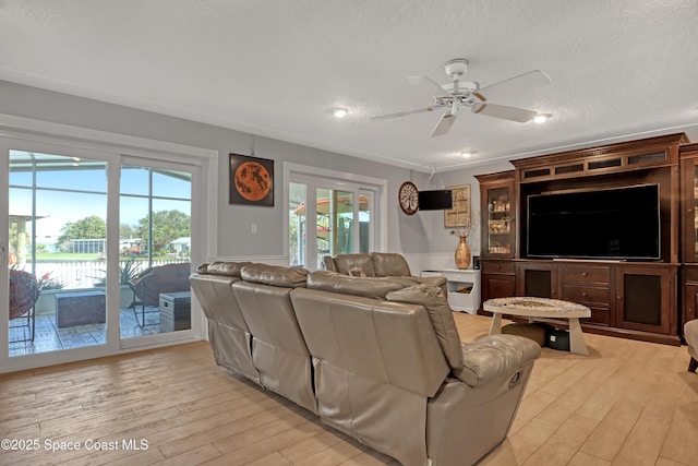 living area with light wood-style flooring, a textured ceiling, and a ceiling fan