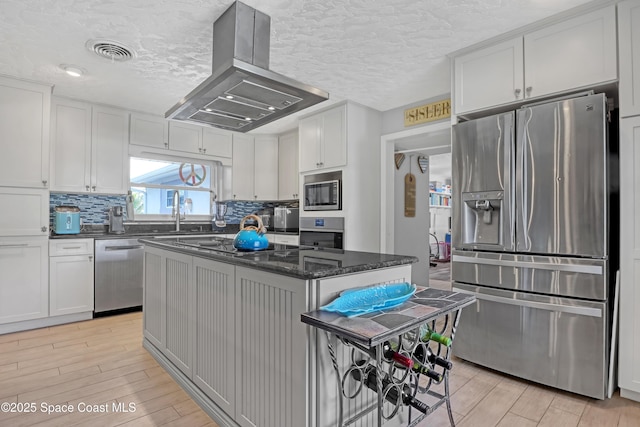 kitchen with wood finish floors, visible vents, island exhaust hood, tasteful backsplash, and stainless steel appliances