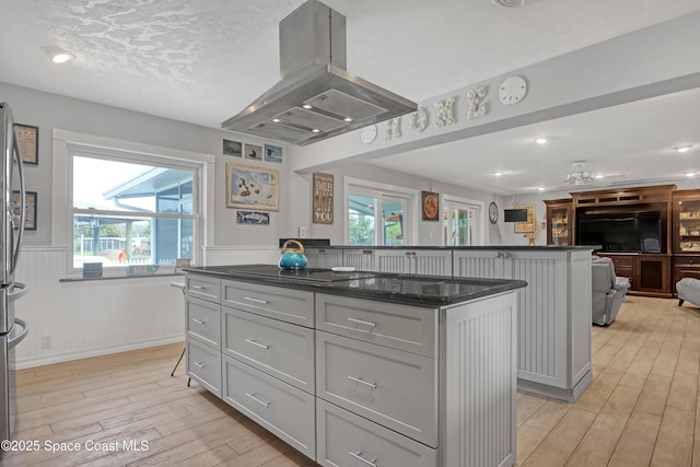 kitchen with island exhaust hood, a kitchen island, gray cabinetry, and open floor plan