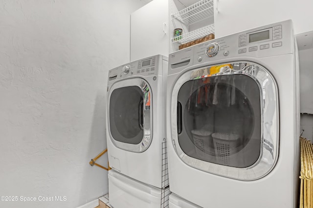 laundry room featuring washing machine and dryer, laundry area, and a textured wall