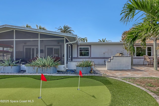 back of property with exterior kitchen, a patio area, a sunroom, and stucco siding