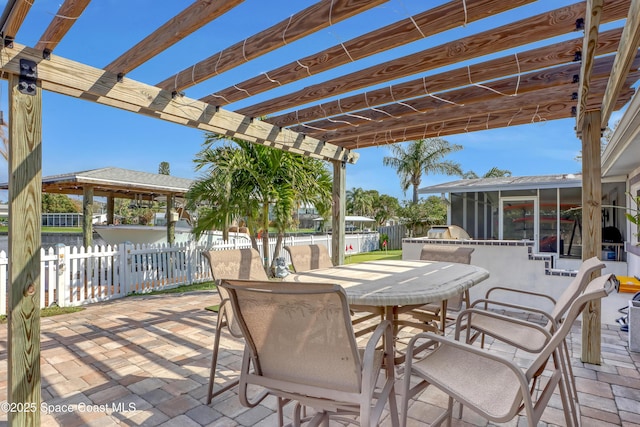 view of patio / terrace featuring a sunroom, fence, outdoor dining space, and a pergola