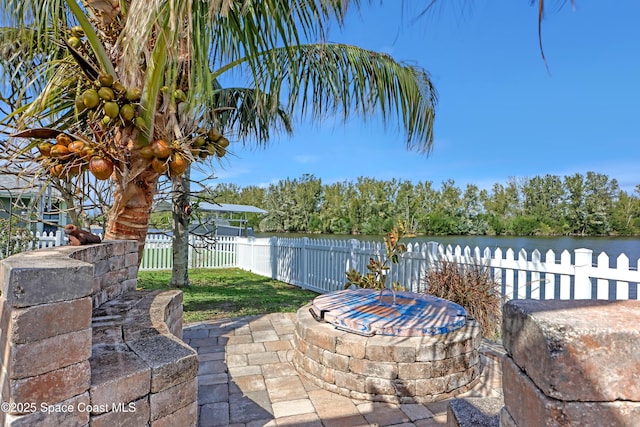 view of patio featuring a water view and fence